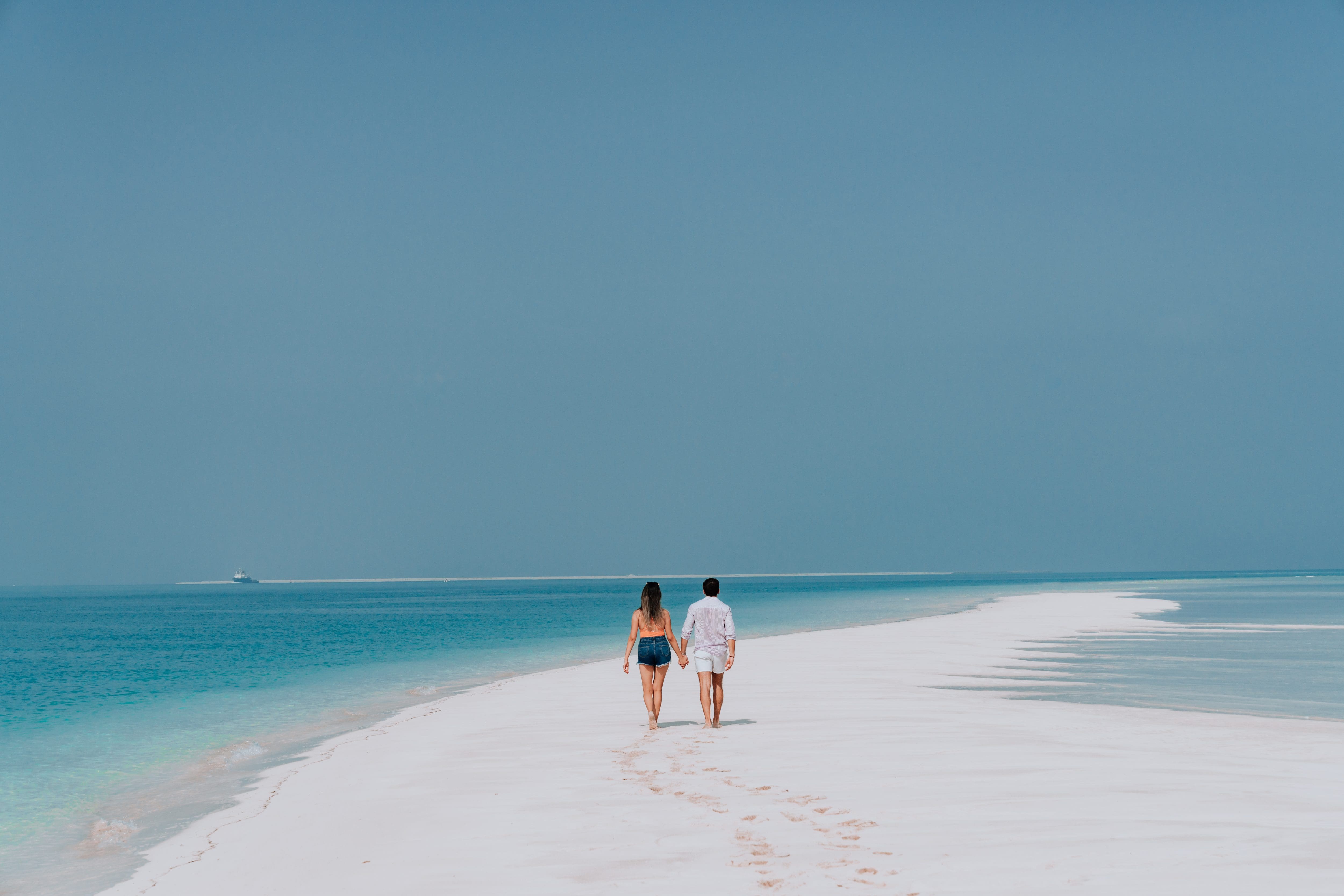 Couple walking on a sandbar in the ocean