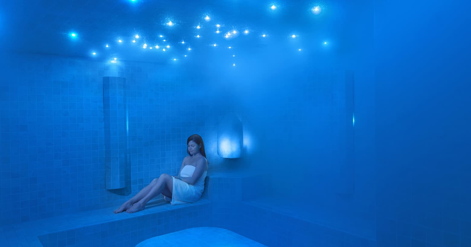 a woman sitting in a blue steam room