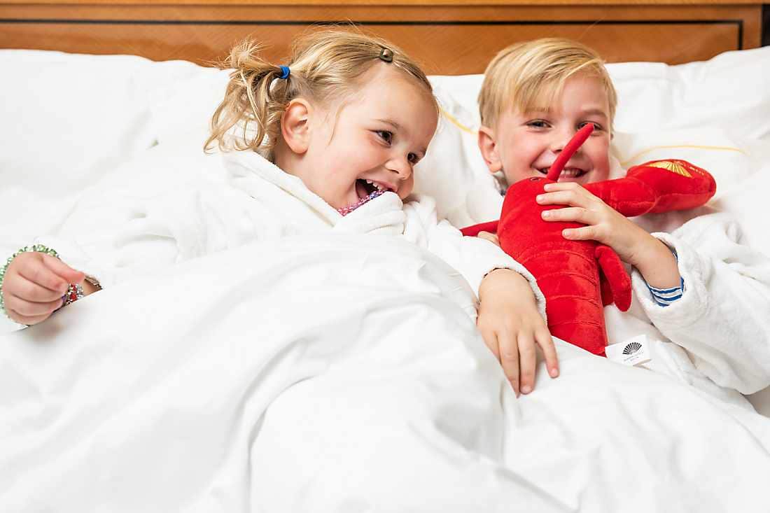 two kids in bed with lobster doll