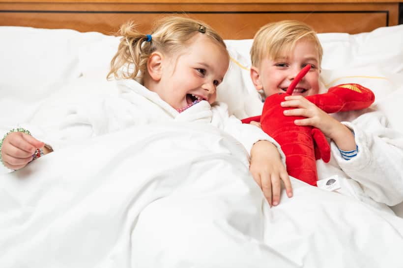dos niños en la cama con una langosta de peluche