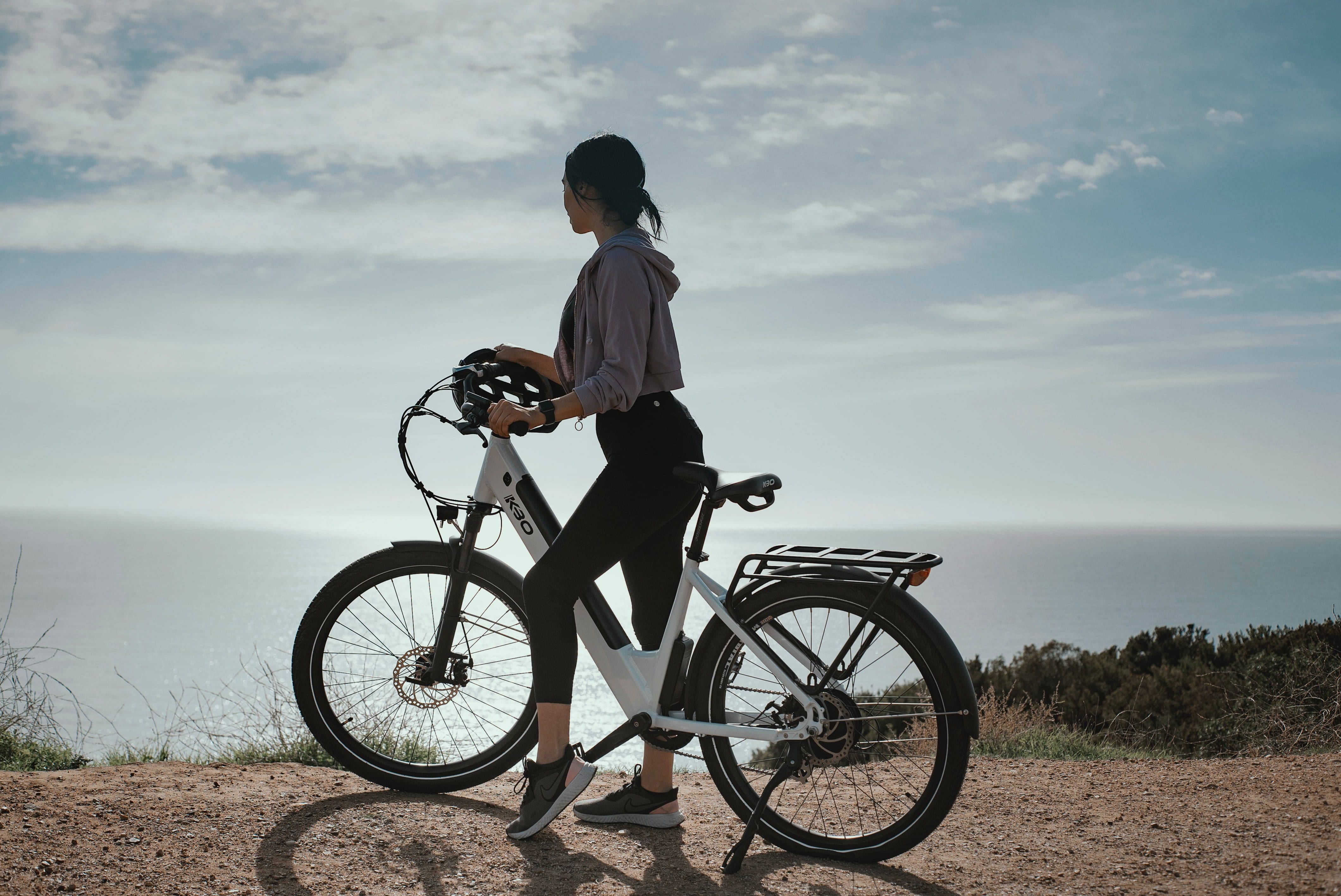 Woman standing with an electric bike overlooking an ocean view