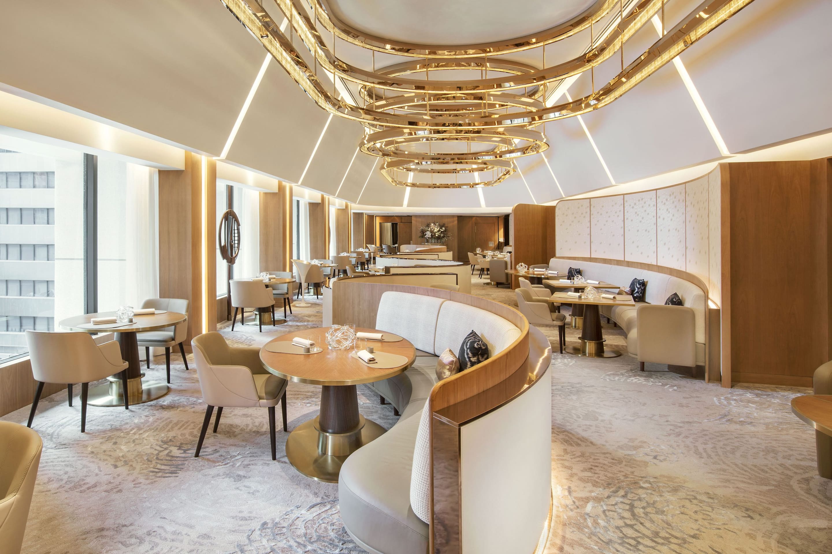 Sleek curved booths and beige hues adorn the interior of Amber at The Landmark, Hong Kong