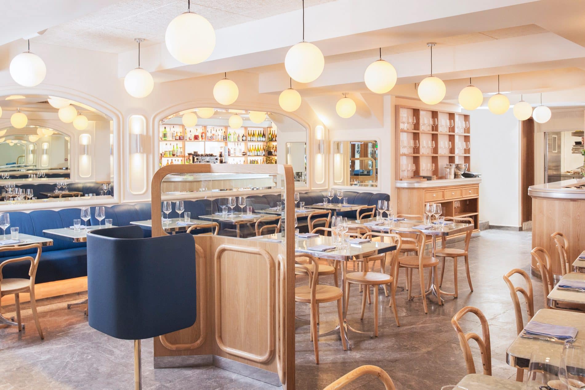 The modern brasserie interiors including blue leather booths and wooden tables at Belon, Hong Kong