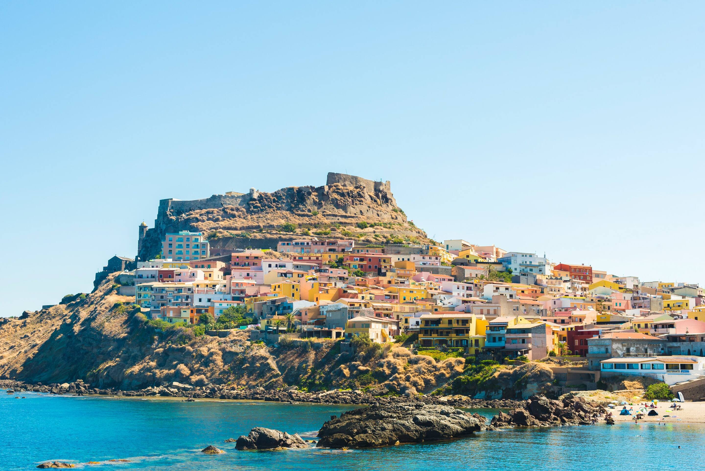 The pastel houses of Castelsardo, Sardinia surrounded by turquoise water