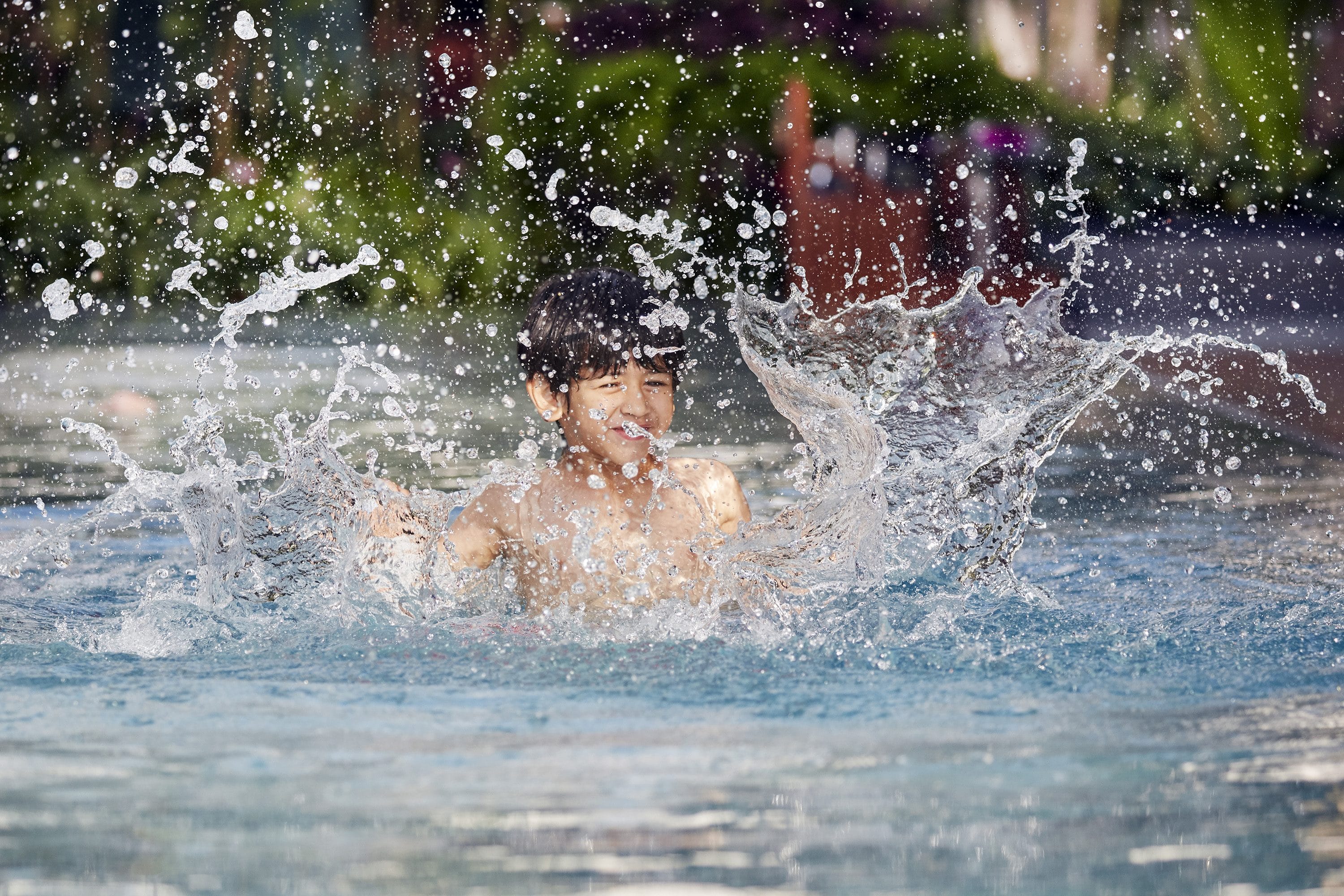 Child splashes in swimming pool