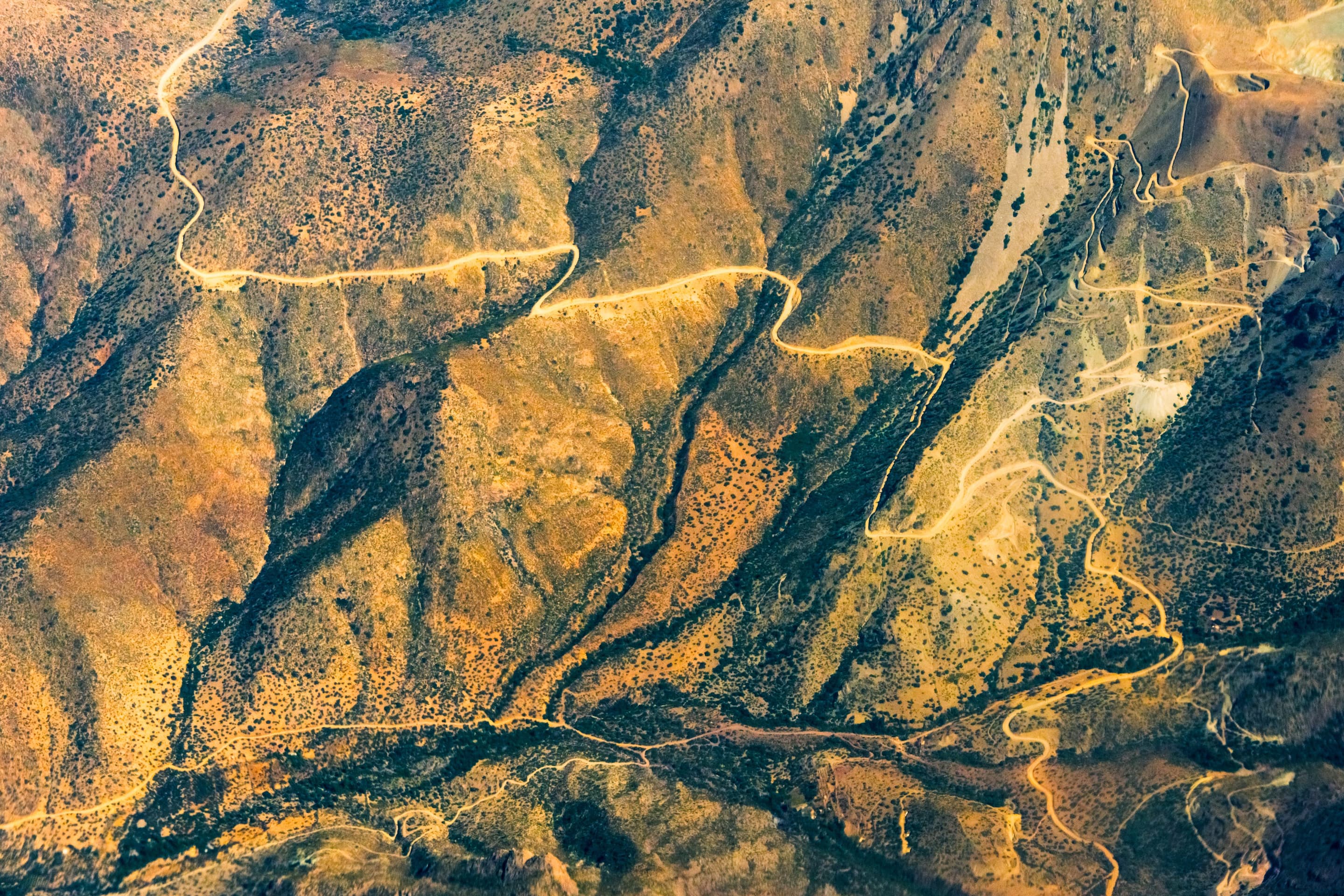 Aerial view of roads winding across rugged mountainous terrain