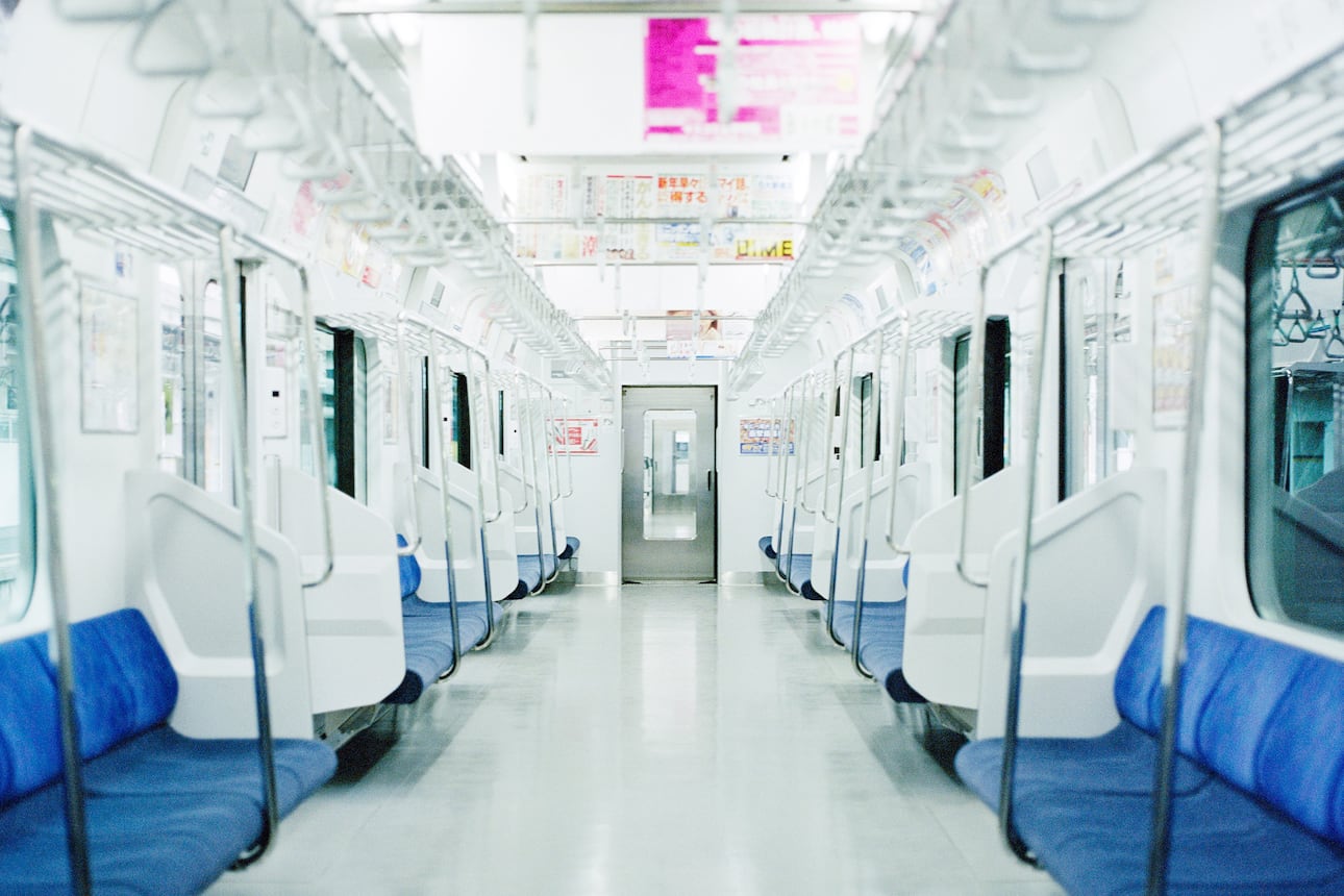 Looking down a bright white carriage of a Tokyo Metro train