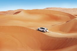 Car driving across a sand dune in Dubai 