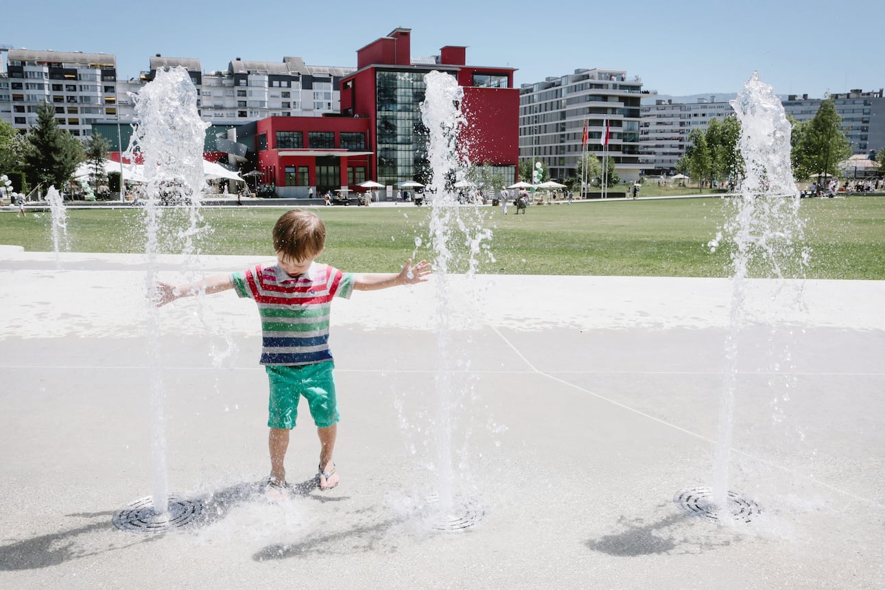 A child plays in a water fountain in Geneva 