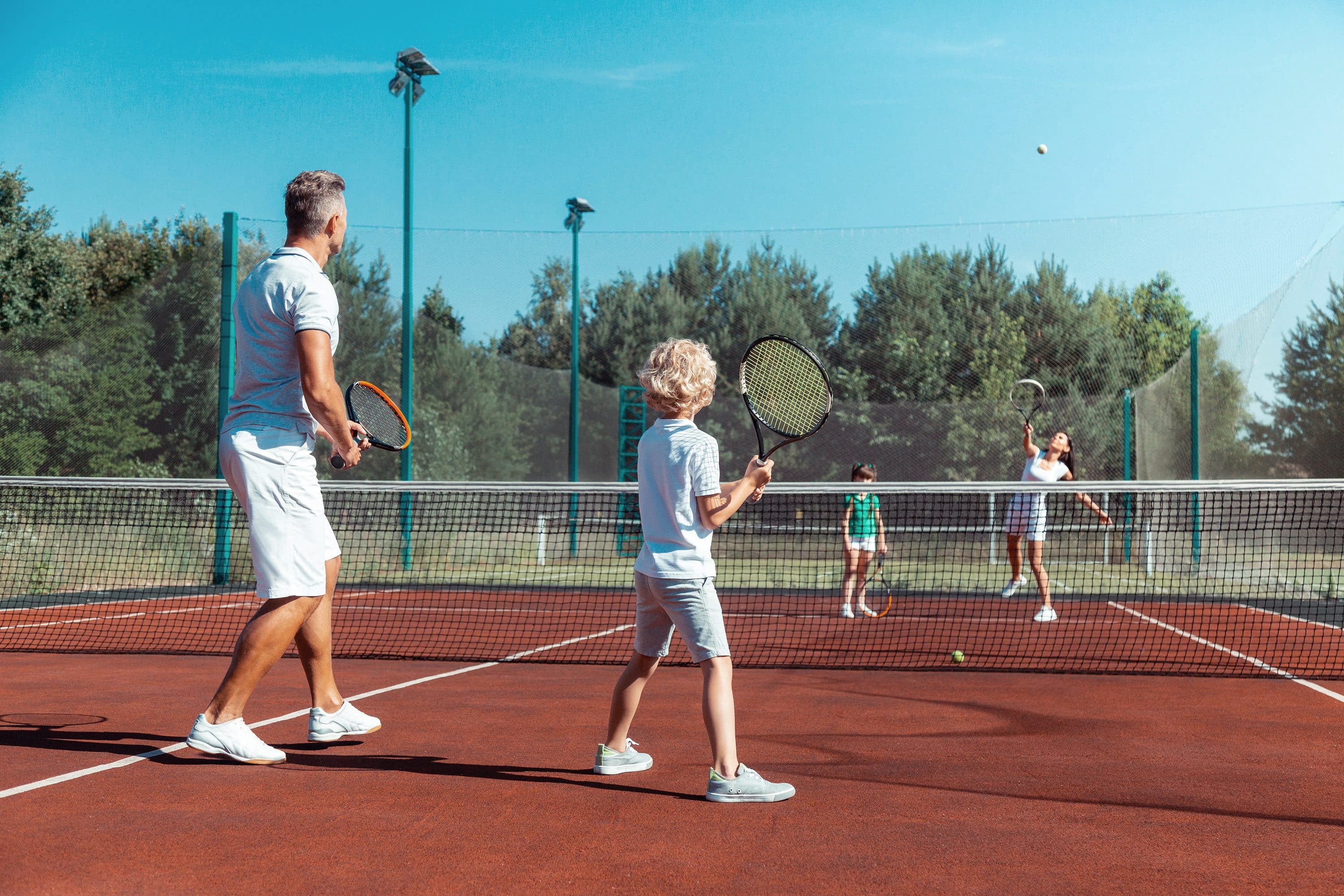 Father and child playing tennis on a court